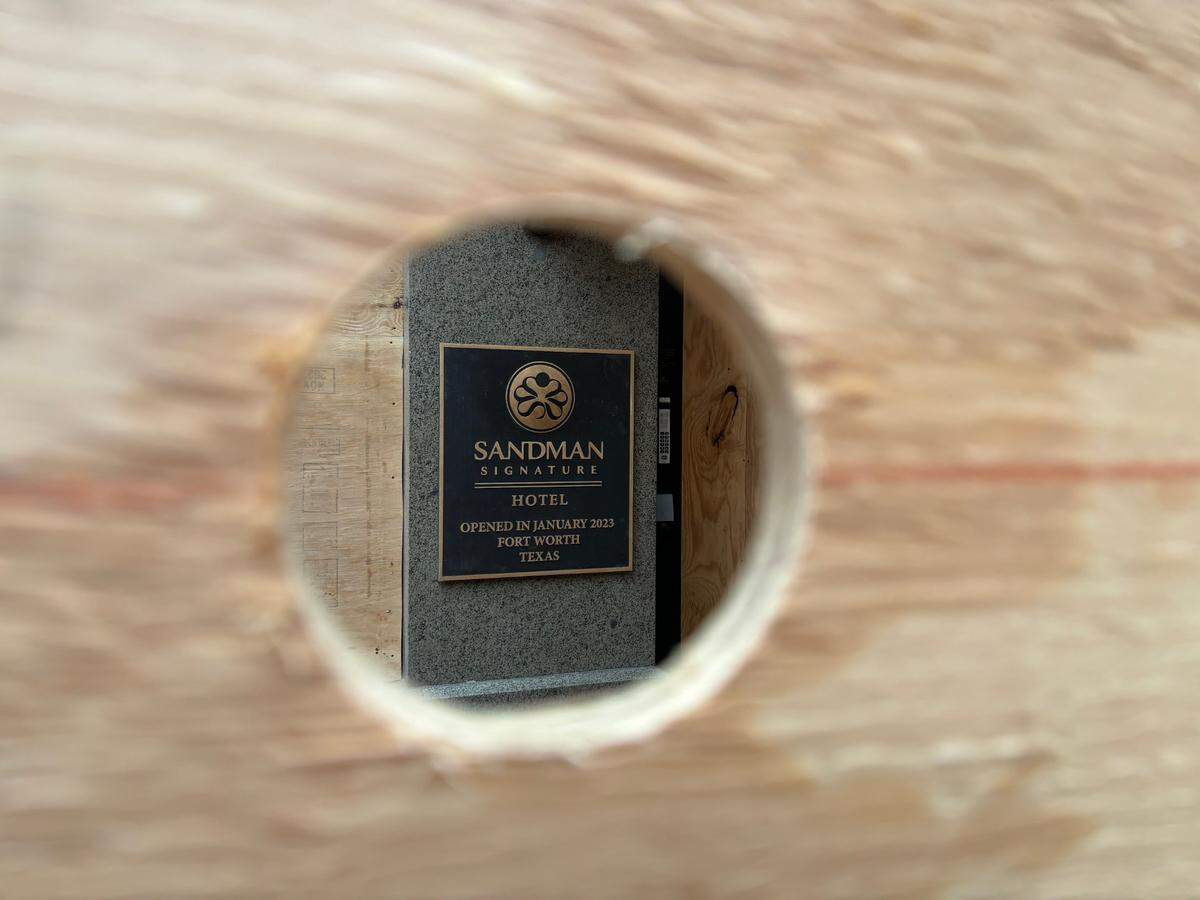 A plaque commemorating the opening of the Sandman Signature Hotel is seen through a hole in the plywood barrier erected around the building’s Houston Street entrance following the explosion there on Jan. 8, 2024.