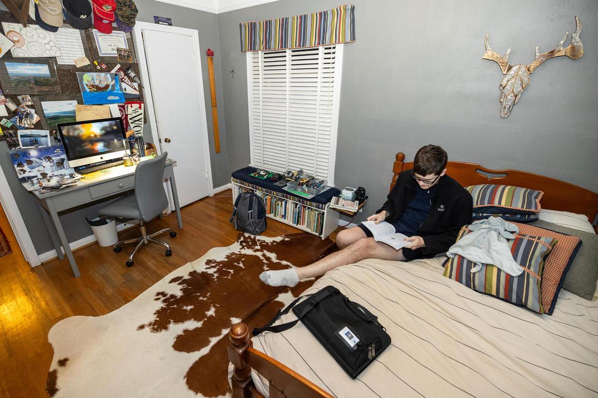 High school sophomore Andrew James, 16, reads one of his many required reading books in his room at his family’s home in Fort Worth on Dec. 12, 2024.