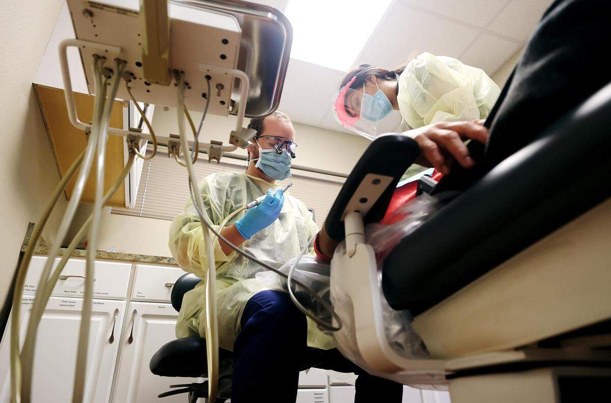 Dr. Scott Stewart, left, a volunteer dentist at Mercy Clinic, fills a cavity for patient Jose Guerrero with the help of dental assistant trainee Jocelyn Mandujano, right, in November in Fort Worth. Mercy Clinic provides free health care, including dental, for uninsured patients in south Fort Worth.