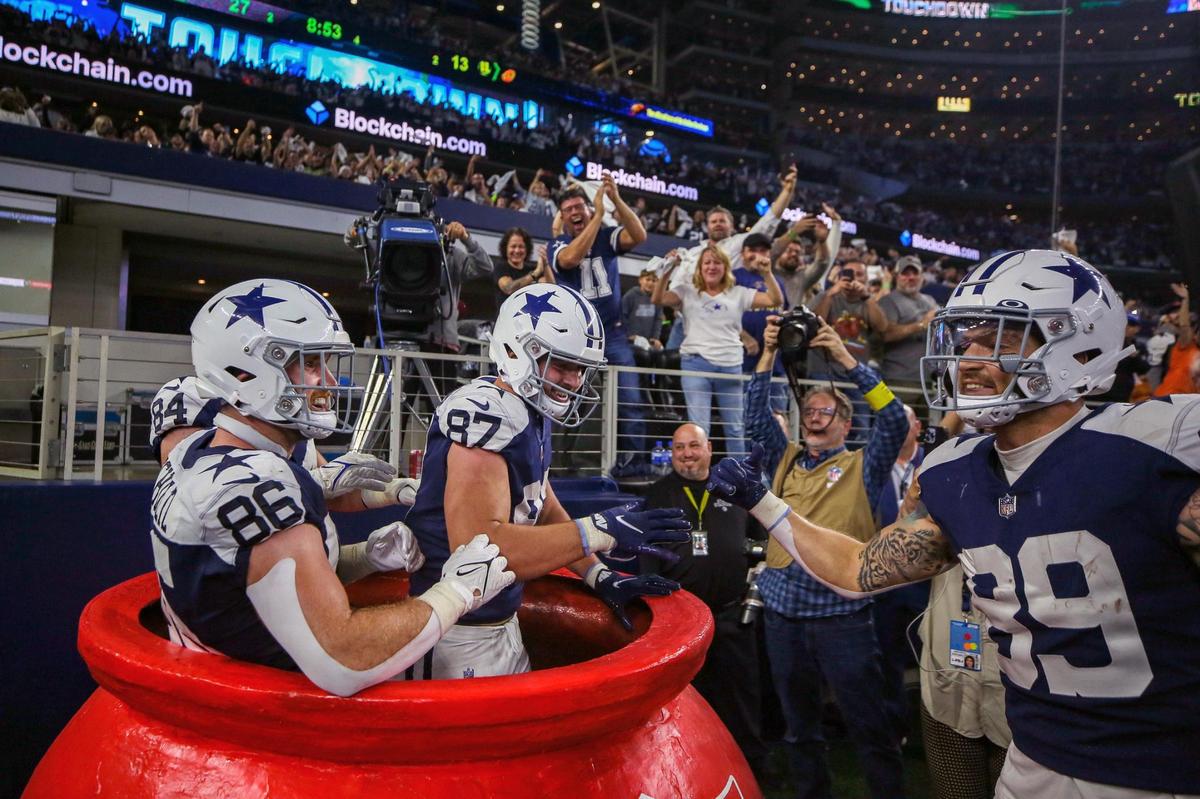 Dallas Cowboys tight ends Dalton Schultz, Sean McKeon, and Jake Ferguson leap into the giant Salvation Army red kettle after Dallas Cowboys tight end Peyton Hendershot scored a touchdown during their game against the Giants at the AT&T Stadium in Arlington on Thursday, Nov. 24, 2022.