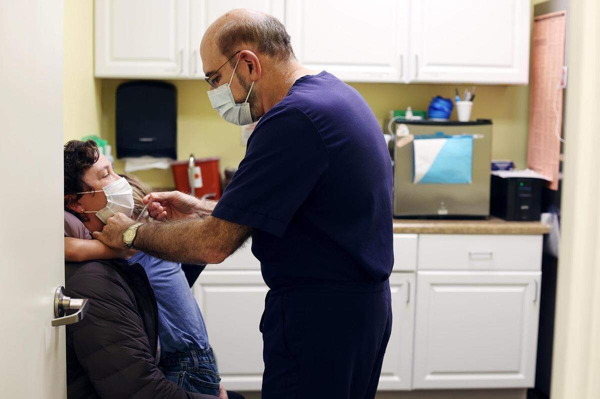 Dr. Steven Levy gives Corinne Van Arman, 7, her first dose of the pediatric COVID-19 vaccine while her mother, Bonnie Fontana, holds her at Lone Star Children’s Medical Clinic at La Gran Plaza.