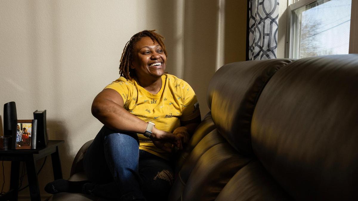 Fort Worth resident La’Nitra Smith sitting in the living room of her new home nestled behind the I-820 highway on Saturday, Feb. 1, 2025. Smith purchased the home in June, with the help of Trinity Habitat for Humanity.