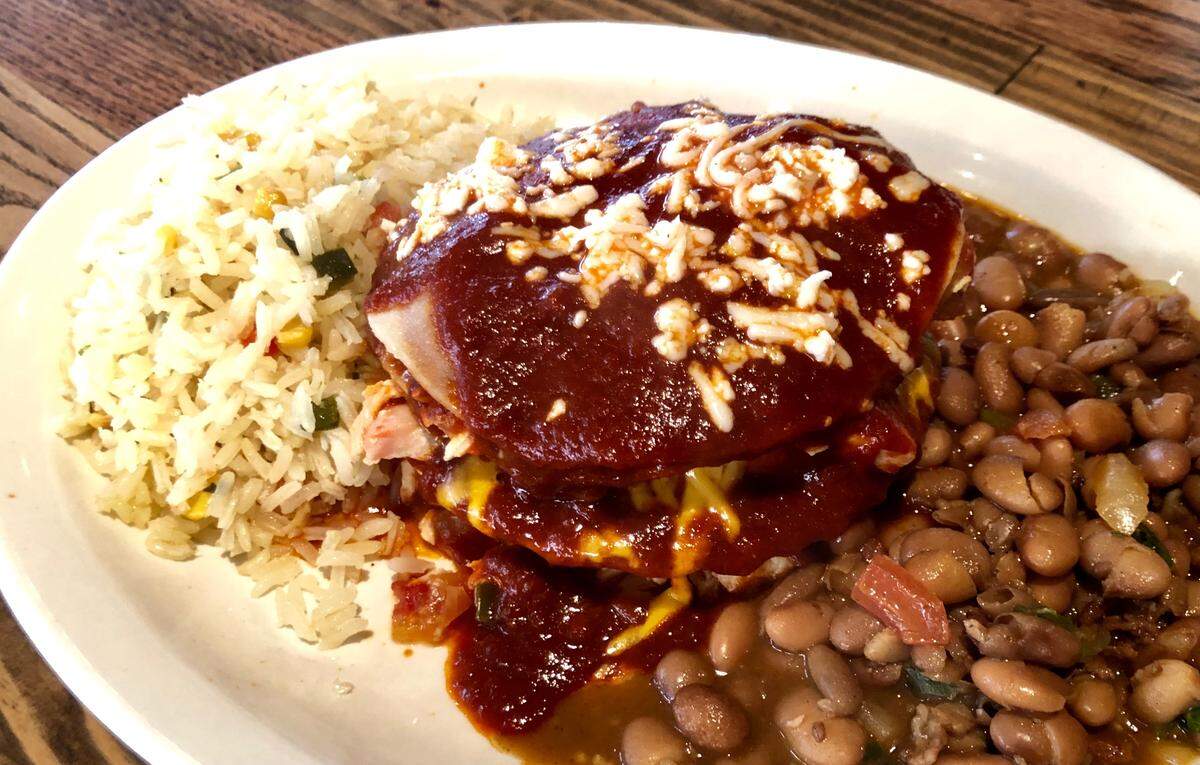 The red chile-chicken stacked enchiladas are one of the “Texican” dishes at Herencia Texican.