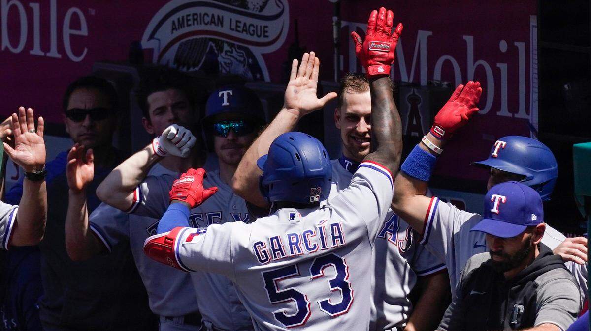 Texas Rangers’ Adolis Garcia celebrates with teammates in the dugout after hitting a home run during the fourth inning against the Los Angeles Angels in Anaheim Wednesday afternoon. Garcia is tied for the MLB lead with 16 homers. The Rangers lost 9-8.