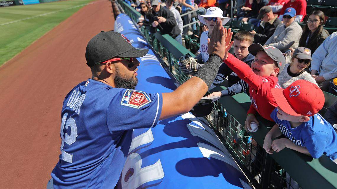 Rangers second baseman Rougned Odor engages with a  young fan at Saturday's spring training opener against the Cubs in Mesa, Ariz.