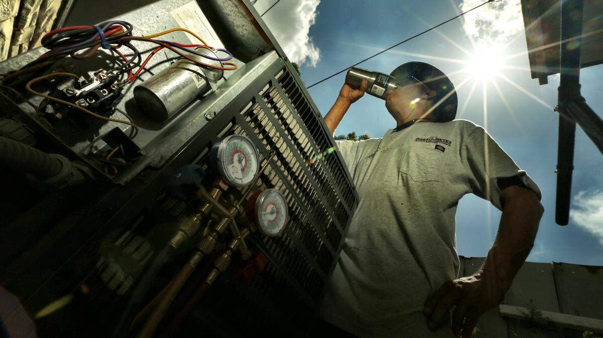 Mike Reyes stays hydrated as he deals with another day of temperatures in the triple digits as he services an air conditioning unit in north Fort Worth, Texas in 2016.  Reyes is the owner of Mike Reyes Air Conditioning.