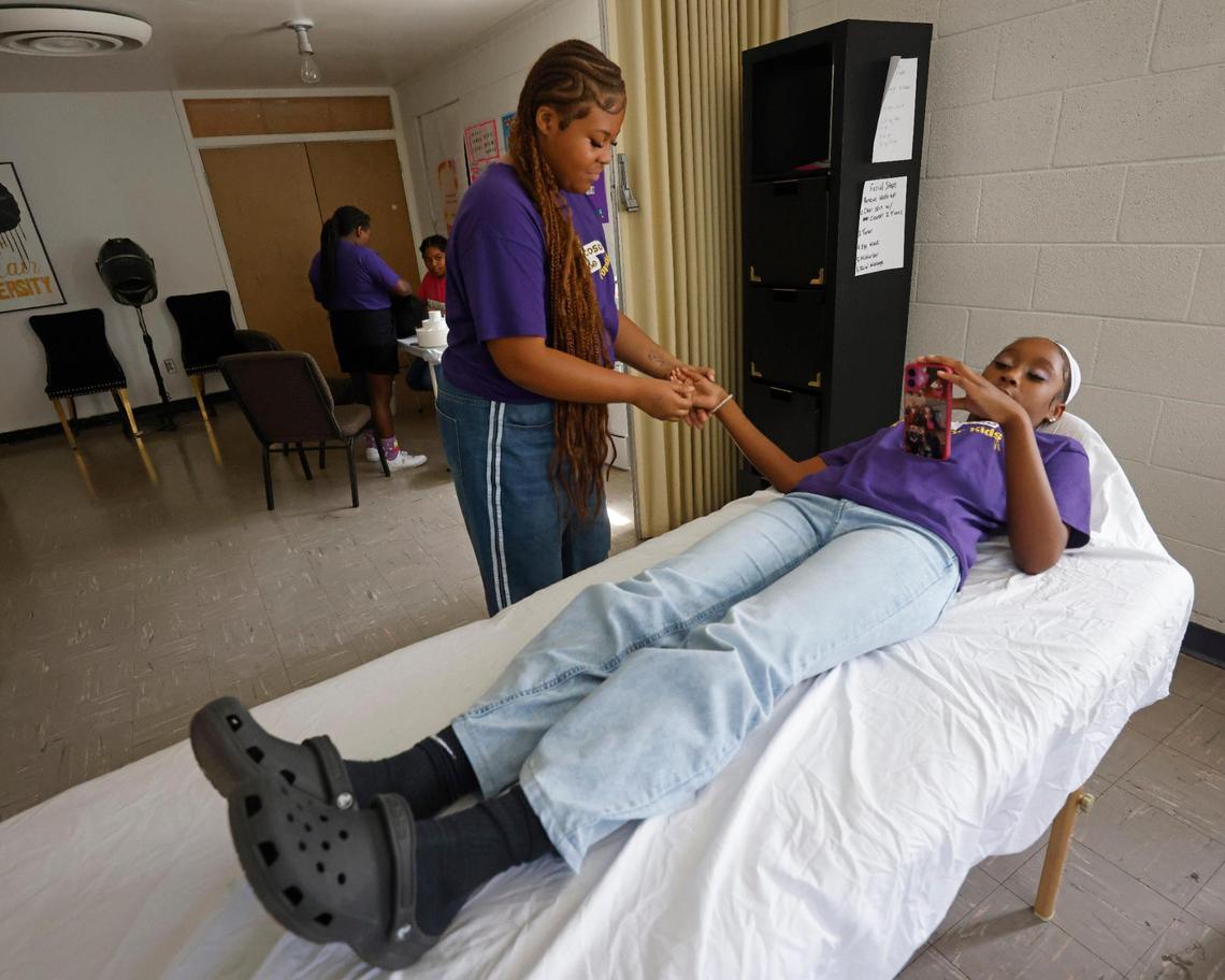 Harleigh Watkins, 14, gives Cookie Foreman, 12, a massage at Next Level Barber and Cosmo camp in Fort Worth.