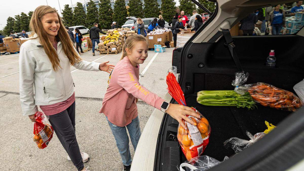 Kristina Costello and her daughter Kallie, 10, put oranges and various Thanksgiving groceries into the trunk of a car during the 4th annual Thanksgiving Mobile food distribution at AT&T Stadium in Arlington on Friday, November 17, 2023.