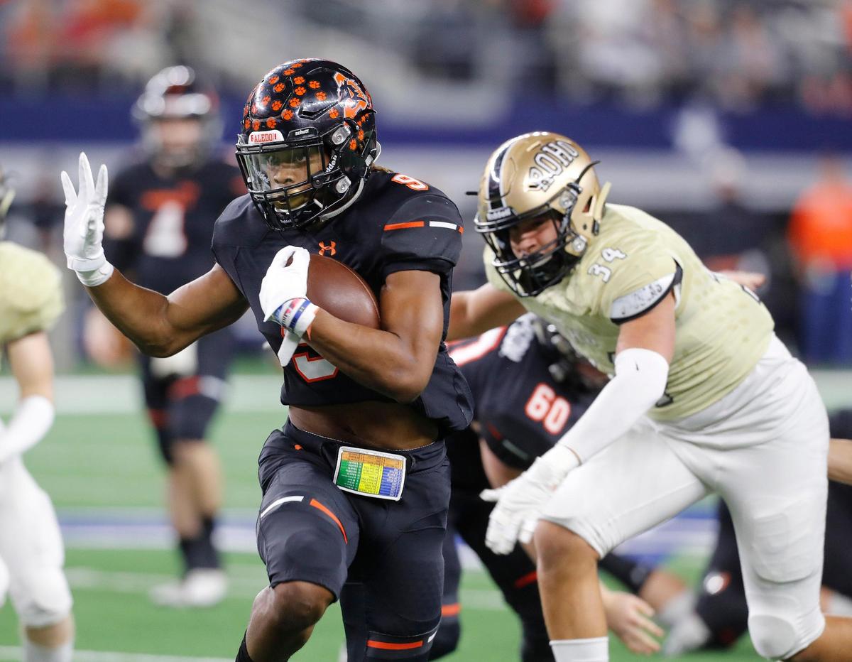 Aledo running back Jase McClellan (9) breaks through the middle for yardage in front of Wichita Falls Rider linebacker Jeremiah Rodriguez (34)in the first half of a high school Class 5A Division II State Semifinals football playoff game at AT&T Stadium, Arlington, Texas, Friday, Dec. 14, 2018. Aledo led 42-0 at the half.