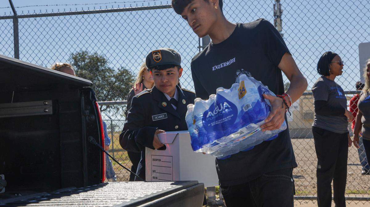 Two teenagers load groceries into the bed of a truck. One is wearing a JROTC uniform.