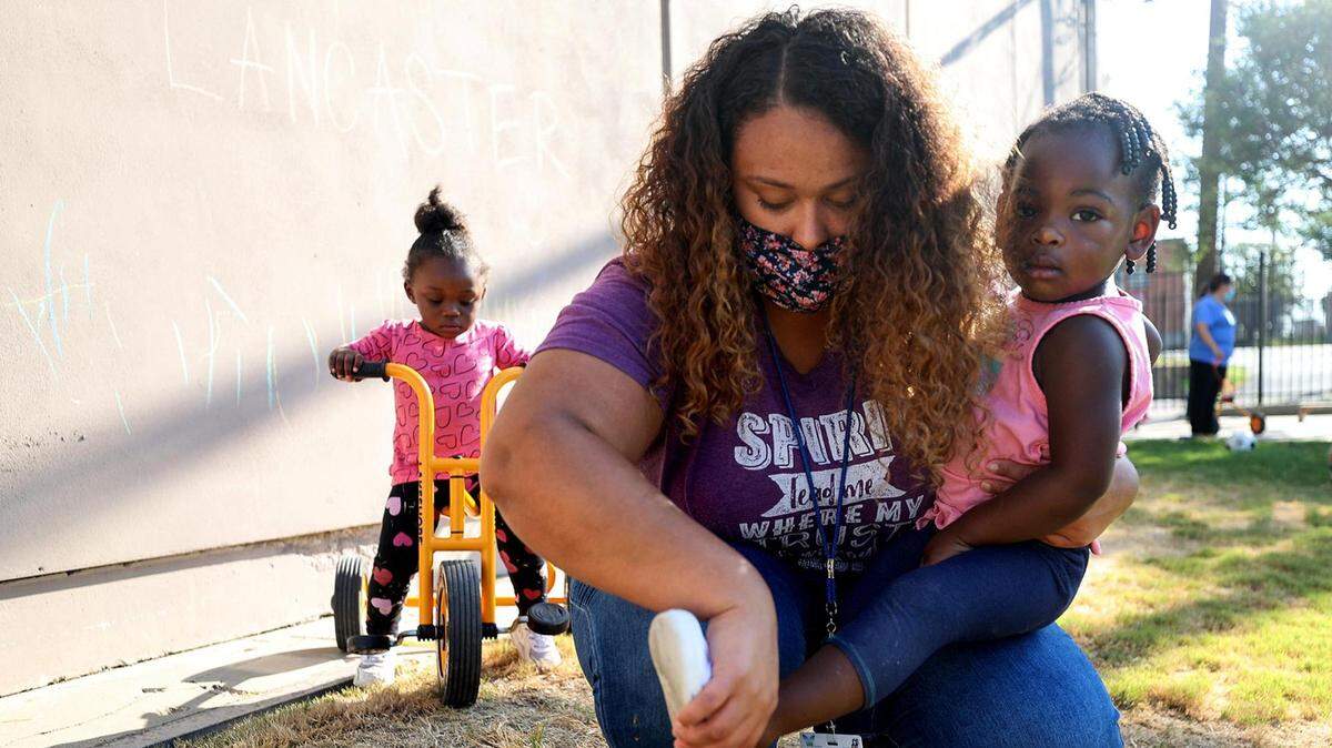 Britain McDowell, an Early Head Start teacher, helps Ashlynn, 2, with her shoe while playing outside at a Center for Transforming Lives’ Early Childhood Education Center in Fort Worth on Sept. 16, 2021. An analysis found most Texas families who received early child tax credit payments used the money for basic needs like childcare, food and housing.