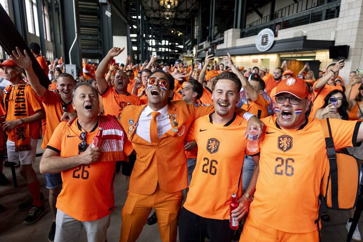 Netherlands soccer dance together before marching to Dallas Stadium ahead of the FIFA World Cup match against Japan on Sunday, June 14, 2026 in Arlington, Texas. The famous double-decker Dutch Orange Bus, or De beroemde Oranjebus, is part of a Netherlands fan tradition bringing a sea of orange to the streets before major soccer matches.