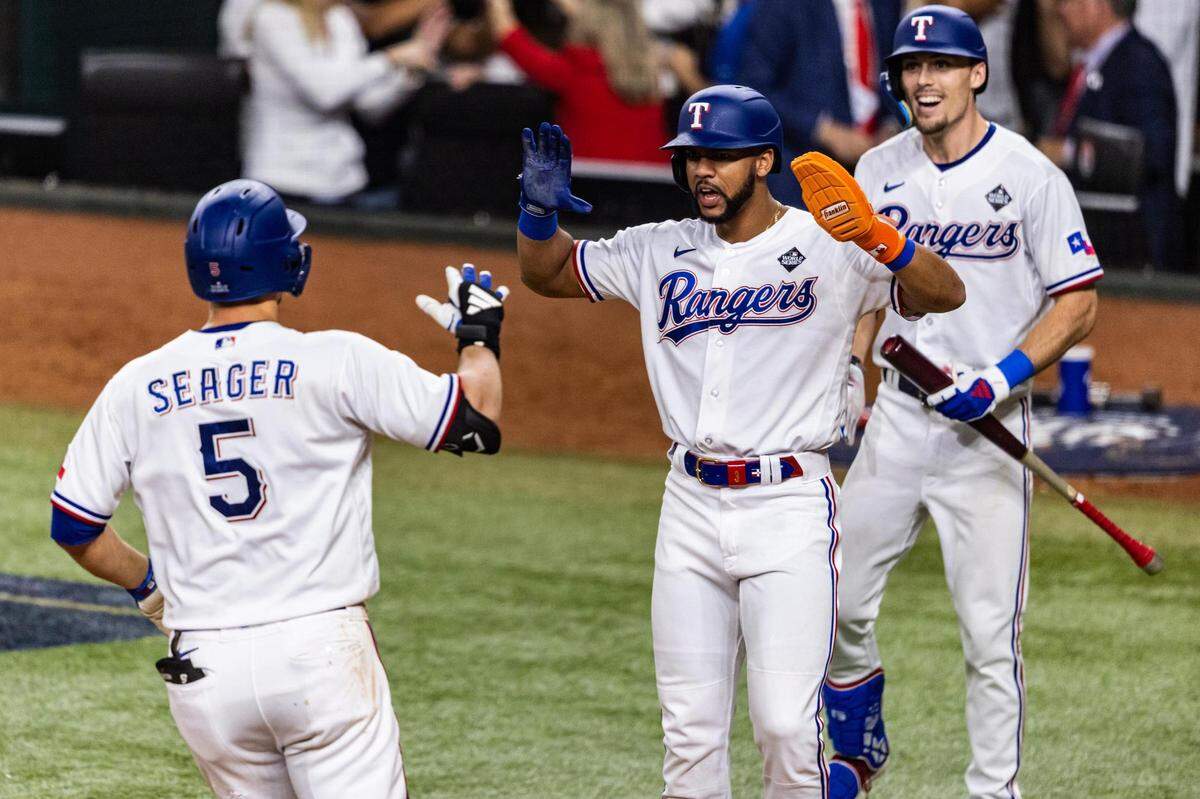 Rangers shortstop Corey Seager (5) celebrates with his teammates Leody Tavares (3) and Evan Carter (32) after hitting a game-tying home run in the ninth inning of Game 1 of the World Series between the Texas Rangers and the Arizona Diamondbacks at Globe Life Field in Arlington on Friday, Oct. 27, 2023.