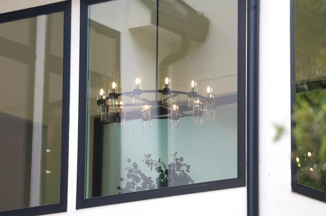 A chandelier hangs in a versatile room with windows on three sides adjacent to the kitchen of a newly built 7,019-square-foot home in the Silverado on the Brazos community in Weatherford on Wednesday, September 11, 2024.