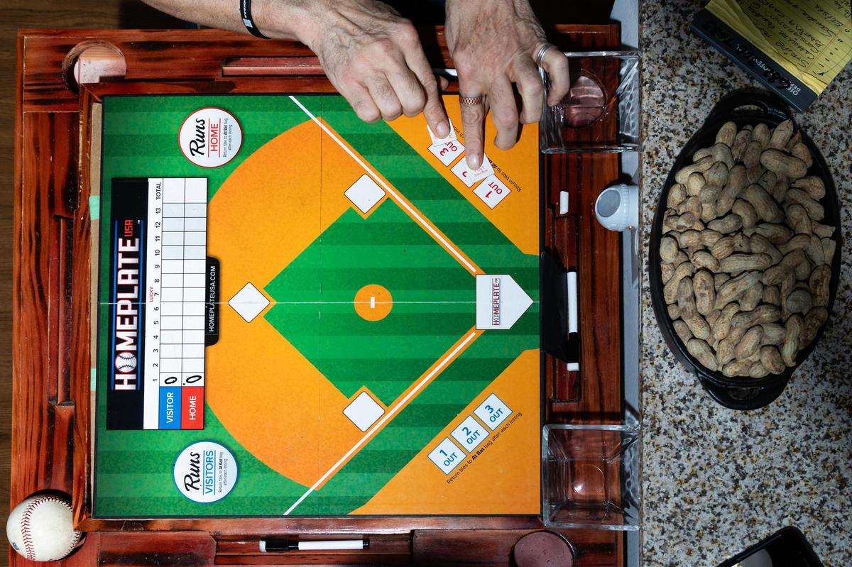 Miguel Otero, the creator of Homeplate USA, shows how the game is played in his apartment in Grapevine on Wednesday, April 16, 2025. Otero invented Homeplate USA, a baseball board game, when he was 11. Now retired at 67, he began producing and selling the game in March out of his apartment.