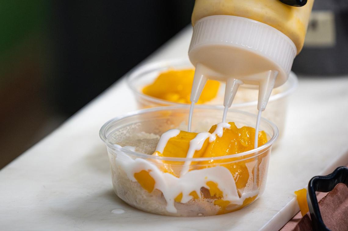 The Mango Sticky Rice dessert is topped with a sweet, coconut sauce prior to being served to a customer at Goldee’s Barbecue in Fort Worth on Friday, June 28, 2024.