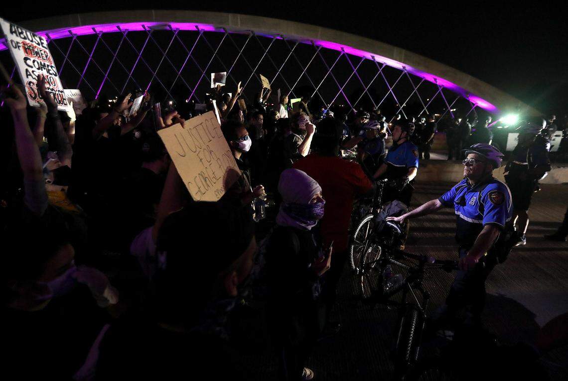 Protesters have a tense exchange with police officers holding them back from crossing the West 7th Street bridge on Sunday, May 31, 2020. Shortly after the police used tear gas to disperse the crowd.