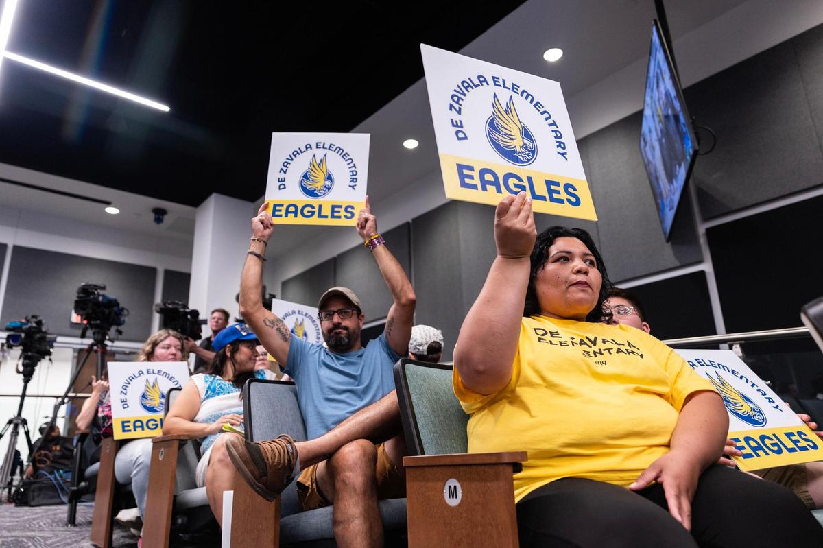 Christian Alvarez, left, and Maria Soto, right, hold signs in support of keeping De Zavala Elementary open during a Fort Worth ISD School Board meeting at the District Administration Building on Tuesday, May 20.