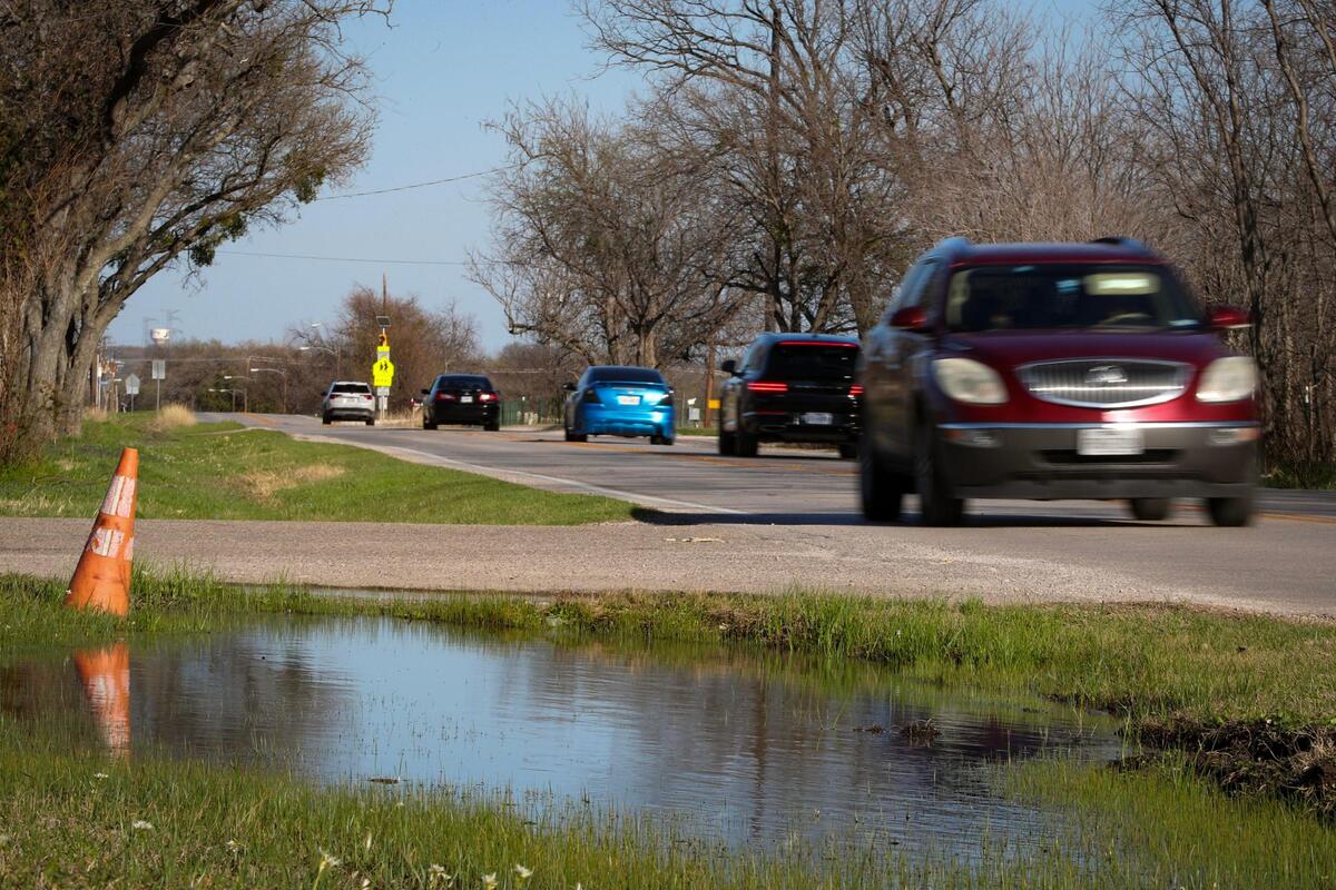 Cars drive past a pool of water after recent heavy rains in Everman, Texas, on Saturday, March 4, 2023. Flooding has been a continuous issue in the city just outside of Fort Worth.