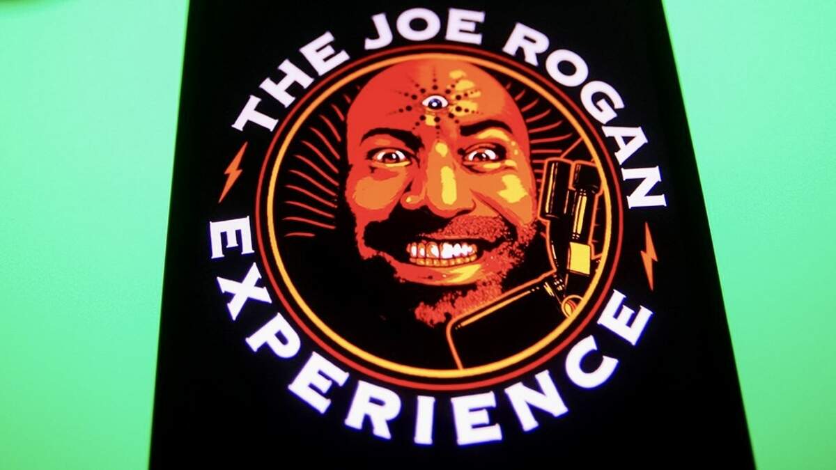 In this photo illustration, The Joe Rogan Experience podcast logo is seen on a smartphone screen with the Spotify logo in the background. 