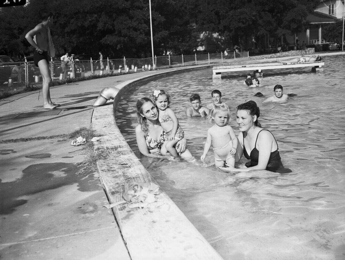 The group is shown happily swimming in the pool while other pool goers look on. Miss McAnnelly and Mrs. Wright are shown wearing bathing suits, with Miss McAnnely's being of a leaf pattern. Mrs. Wright appears to be looking forward while Miss McAnnelly and small Kimmy look on at the camera. To the left of them is another pool goer looking out at the pool.