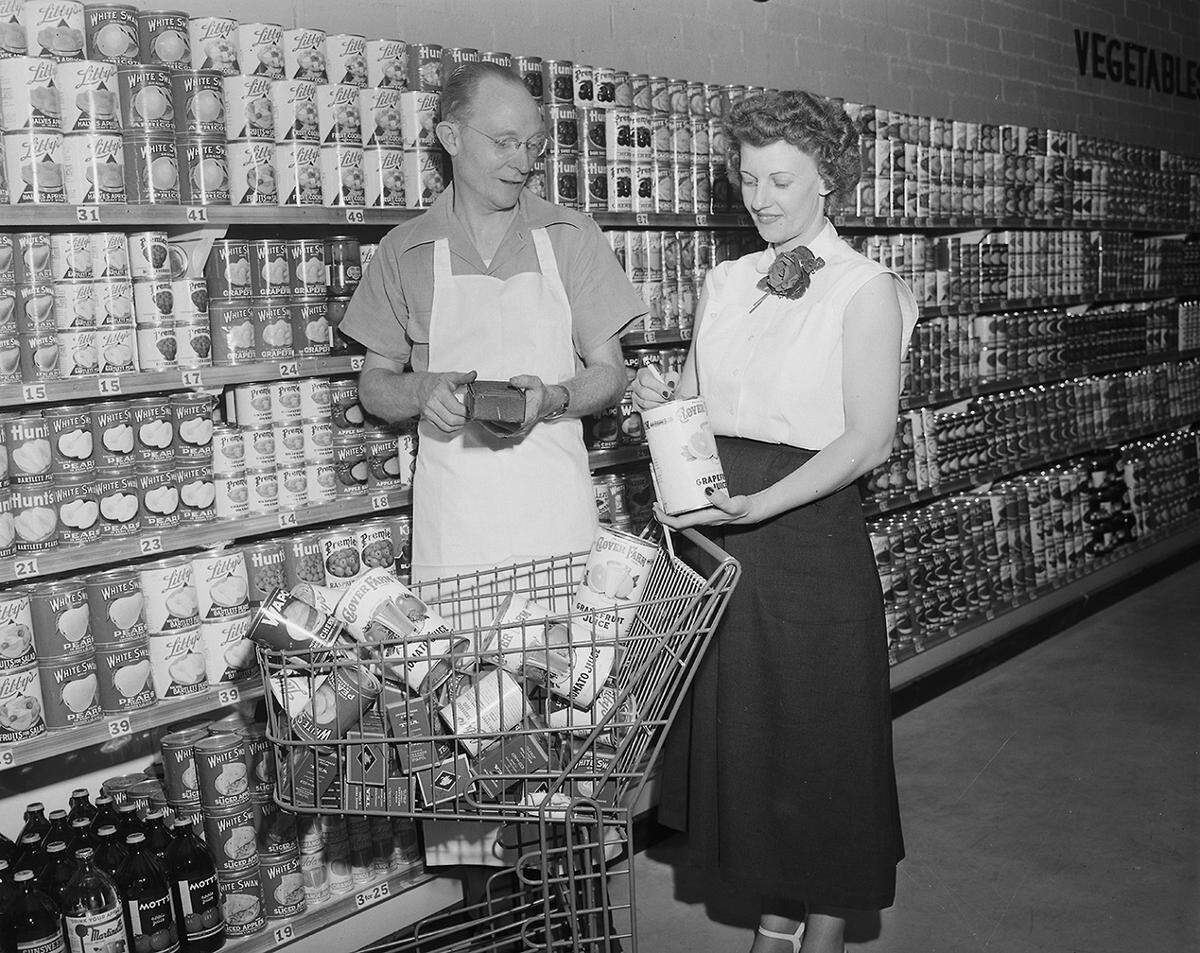 May 31, 1950: Applying a final touch to displays of a new Clover Farm Store at 3705 Ryan Ave. are W.V. Haynie, owner and operator of the modern supermarket, and Mrs. Mary Oswalt, checker. (The site today is Amigo’s Food Mart, at the corner of West Butler Street.)