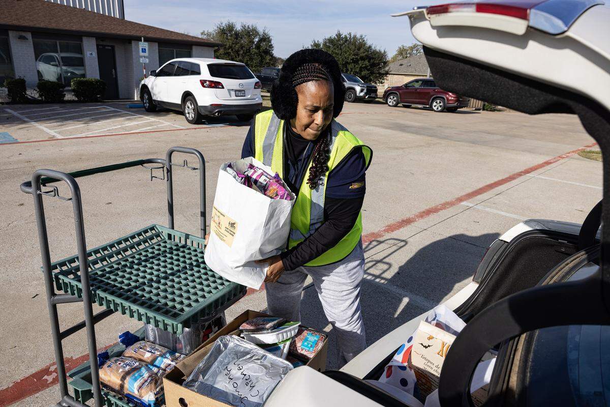 Ramonica Tarrant puts groceries given to her in her car at Him Food Bank Warehouse in Mansfield on Wednesday, Dec. 3, 2025.