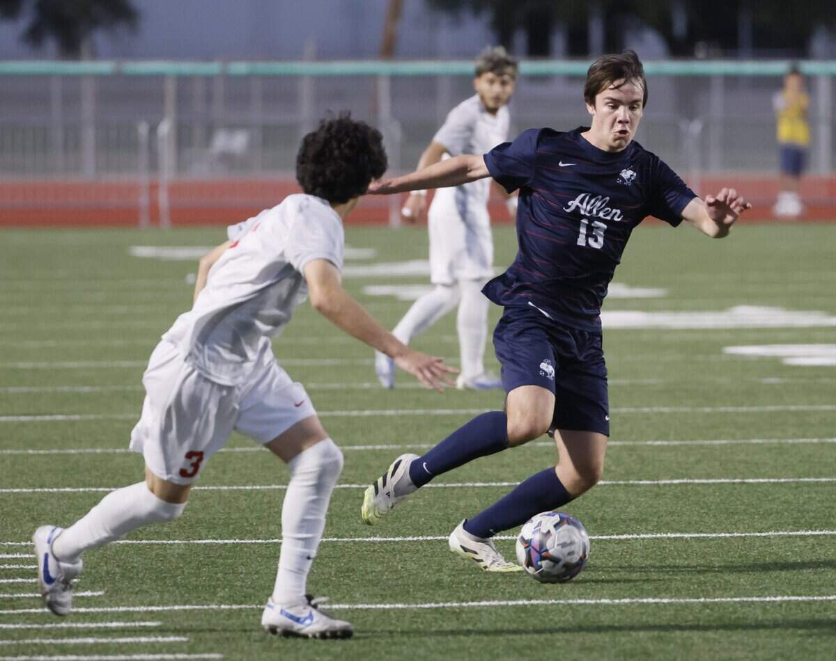 Allen midfielder Hudson Crook (13) crosses the ball in front of Arlington Sam Houston Axel Alvarado (3) during the first half of a UIL area round boys soccer playoff game at Tommy Standridge Stadium in Carrollton, Texas, Tuesday, March 24, 2026.