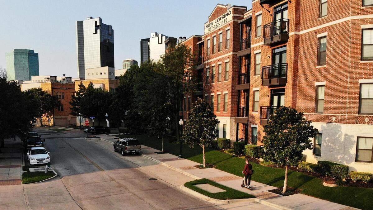 A man rides a scooter down the sidewalk in front of one of the many apartment complexes along the Trinity River near Samuels Avenue. Rental prices continue to rise causing many to struggle to pay rent each month.