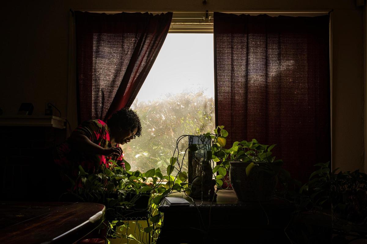 Salillian Parker, the mother of Daniel Reed, waters her plants by the window in the living room of her home in Fort Worth on Aug. 28. Shortly after her son was sentenced, Parker said she cried throughout the day and was barely sleeping. Now that her son is settled, she has begun to help herself as well.