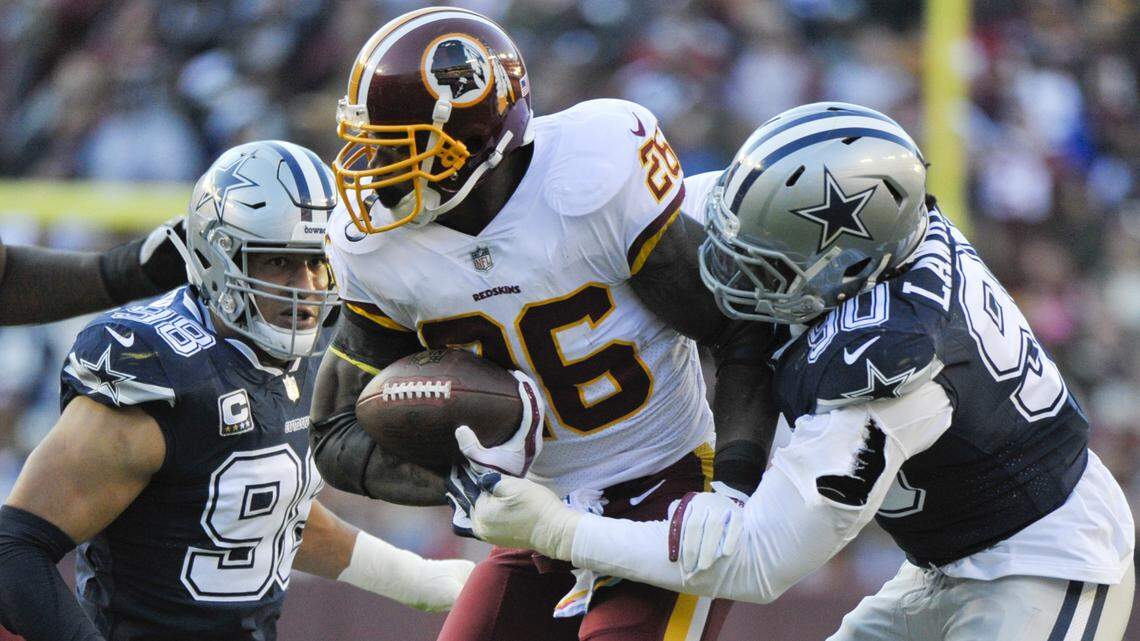 Washington Redskins running back Adrian Peterson runs between Cowboys defensive end Tyrone Crawford, left, and defensive end Demarcus Lawrence during the first half of Sunday’s 20-17 loss.