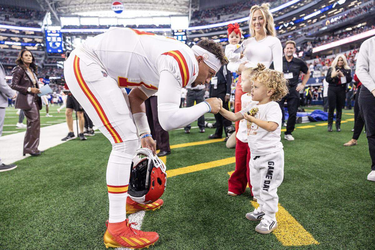 Chiefs quarterback Patrick Mahomes (15) greets his son Patrick "Bronze" Lavon III and his family prior to the first half of an NFL game between the Dallas Cowboys and the Kansas City Chiefs at AT&T Stadium in Arlington on Thursday, Nov. 27, 2025.