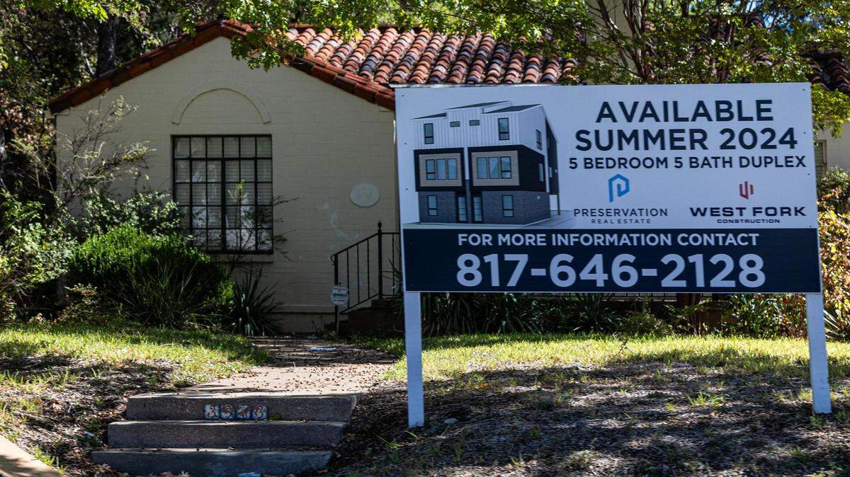 A single story house with a terracotta roof sits behind a "coming soon" sign advertising a boxy duplex targeted at college students. 