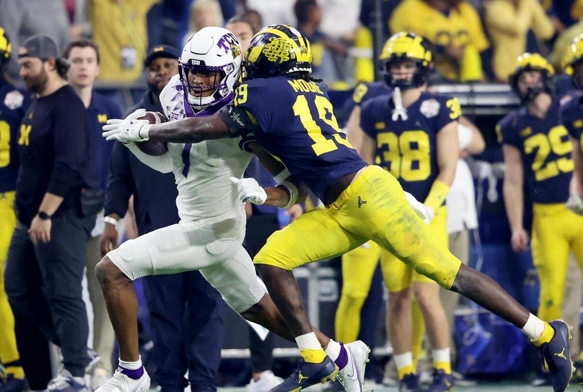 TCU wide receiver Quentin Johnston runs the ball as Michigabn defensive back Rod Moore gets an arm around him at the Vrbo Fiesta Bowl at State Farm Stadium in Glendale, Ariz., on Saturday, December 31, 2022.