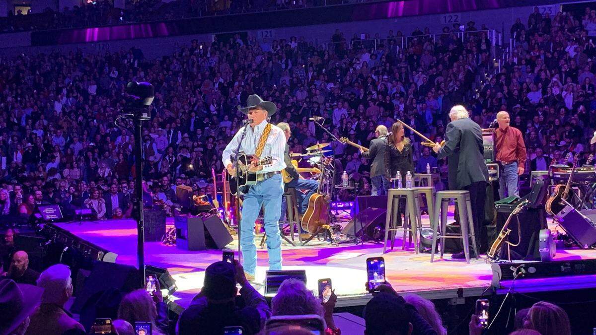 George Strait singing and strumming a guitar on stage at Dickies Arena.