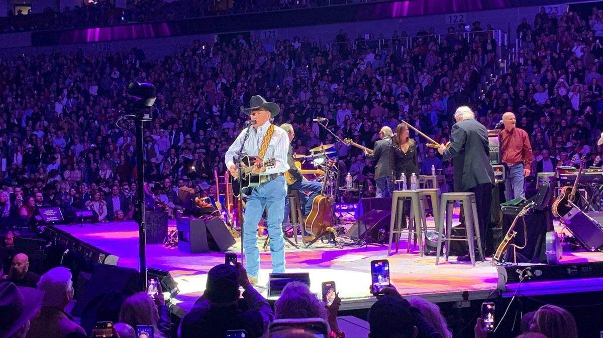 George Strait singing and strumming a guitar on stage at Dickies Arena.