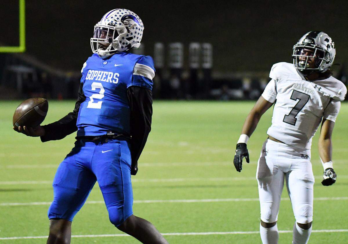Grand Prairie quarterback Savion Red, left, reacts after going one yard for the touchdown to cut the Arlington Martin lead 21-7 as Martin’s Chris Johnson watches on in the second quarter of their district 8-6A football game Friday, October 29, 2021 at the Gopher Warrior Bowl in Grand Prairie, Texas. Special/Bob Haynes