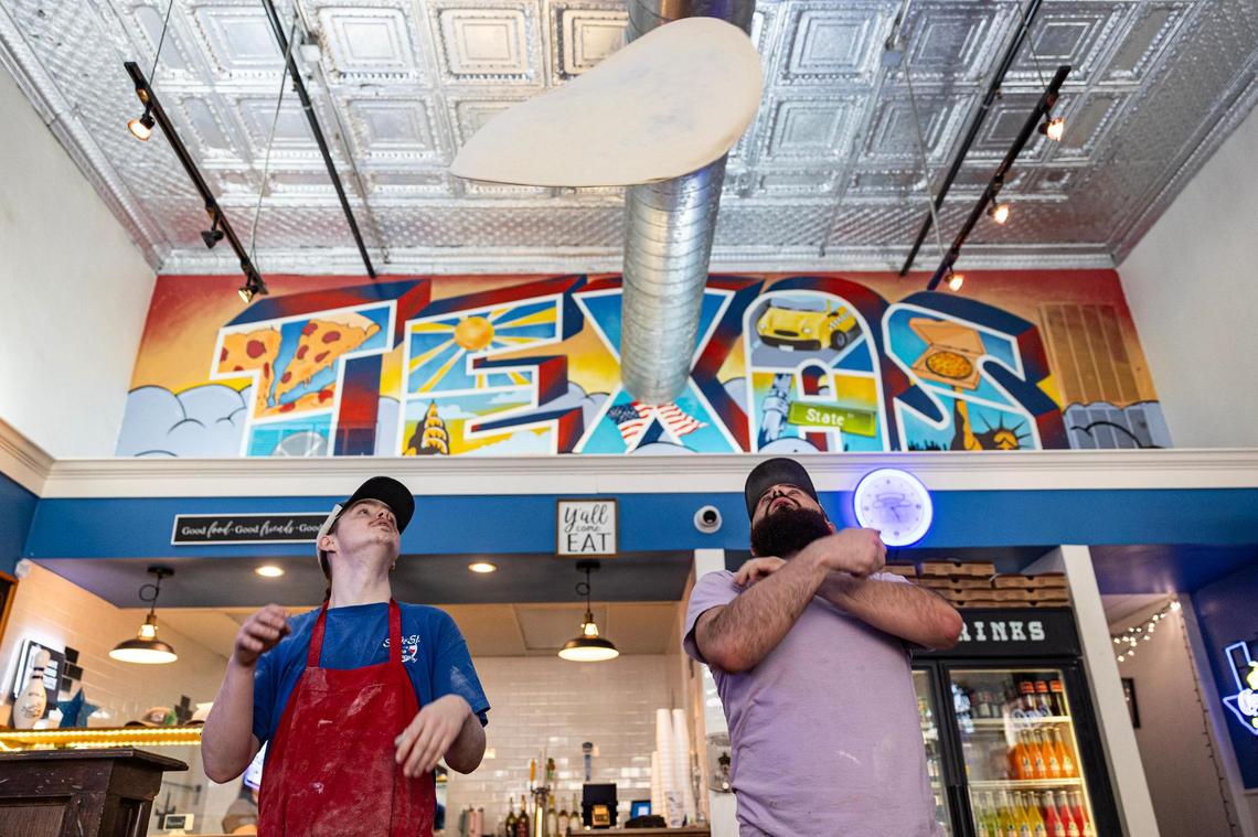 Pizza maker Kolby Hamblin, left, prepares to catch a dough tossed in the air by kitchen manager Trey Pittman in the dining room at State Street Pizza Company in Decatur on Saturday, March 29, 2025.