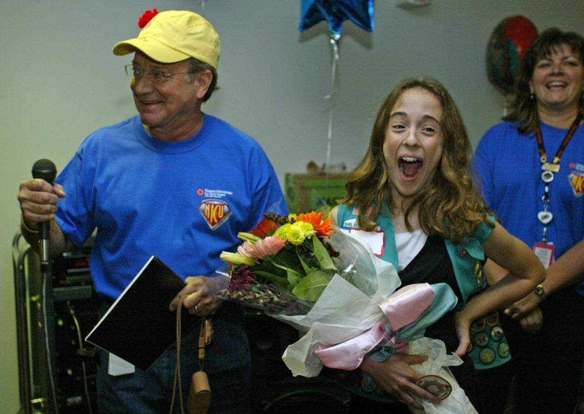 April 28, 2006: Kate McCasland, 11, reacts with surprise after her neonatologist, Dr. Samuel Juliao, told her mom that she needed to worry now that Kate will be able to drive soon. Kate earned her Bronze Award in Girl Scouts by knitting caps for the babies in the neonatal ICU at Harris Methodist Hospital in Fort Worth. She was presented the award at the neonatal reunion. McCasland’s goal was to knit 104 caps to match the number of days she was in the NICU. She knitted 112 herself and enlisted her friends at Park Wood Nursing home to help bringing her total to 251 hats, 16 blankets, and 6 pairs of booties.