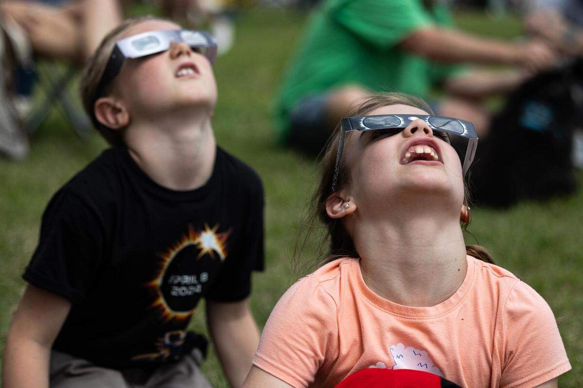 Dean Dinino, 7, and Ada June, 8, put on their eclipse glasses to look at the Great North American Eclipse in Hillsboro on Monday, April 8, 2024.