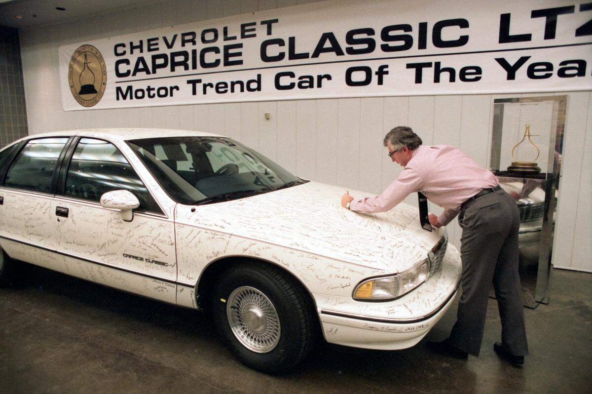 March 10, 1991: Al Poppitt autographs a Chevrolet Caprice Classic at the General Motors plant in Arlington that is adorned with hundreds of signatures after being named the 1991 Motor Trend Car of the Year.
