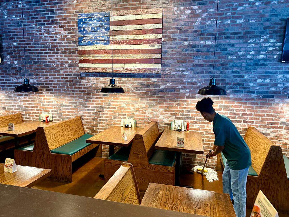 A worker mops up near closing time for Snuffer’s Restaurant & Bar in Colleyville, Texas, going out of business June 22, 2025.