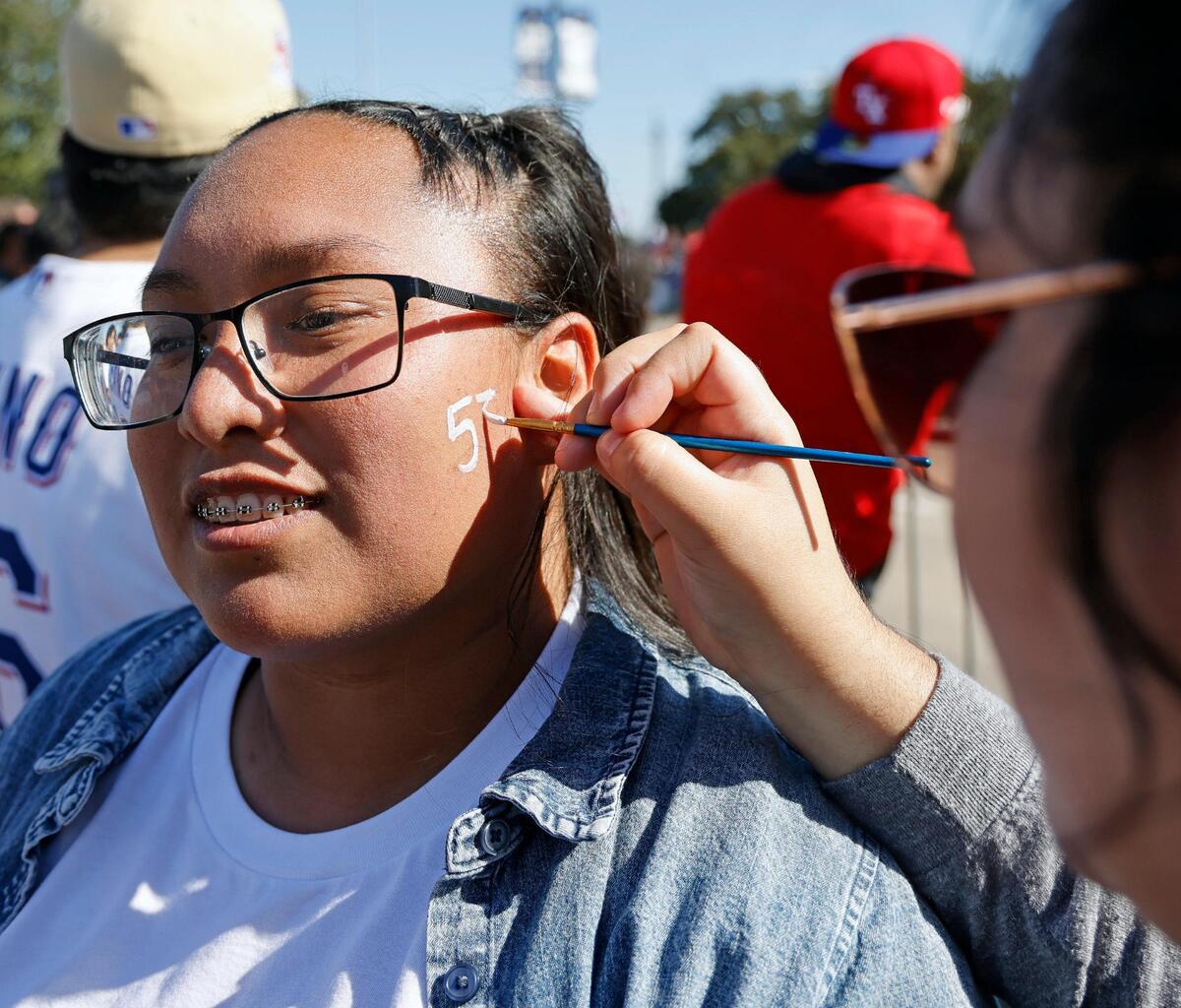 Stephanie Hernandez face paints Edith Tovar’s favorite Ranger’s number on her cheek during the Texas Rangers World Series Parade in Arlington, Texas, Friday, Nov. 03, 2023. (Special to the Star-Telegram Bob Booth)