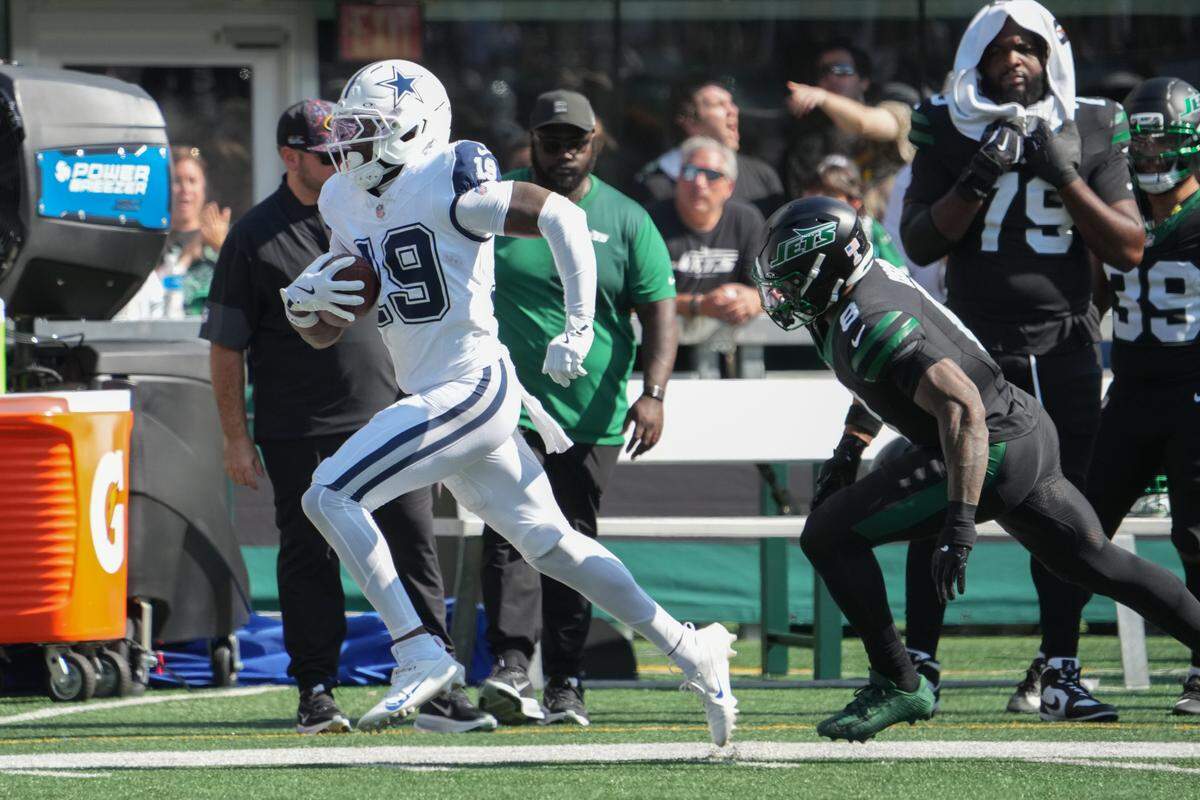 Oct 5, 2025; East Rutherford, New Jersey, USA; Dallas Cowboys wide receiver Ryan Flournoy (19) runs with the ball as New York Jets safety Andre Cisco (8) defends during the first half at MetLife Stadium. Mandatory Credit: Robert Deutsch-Imagn Images