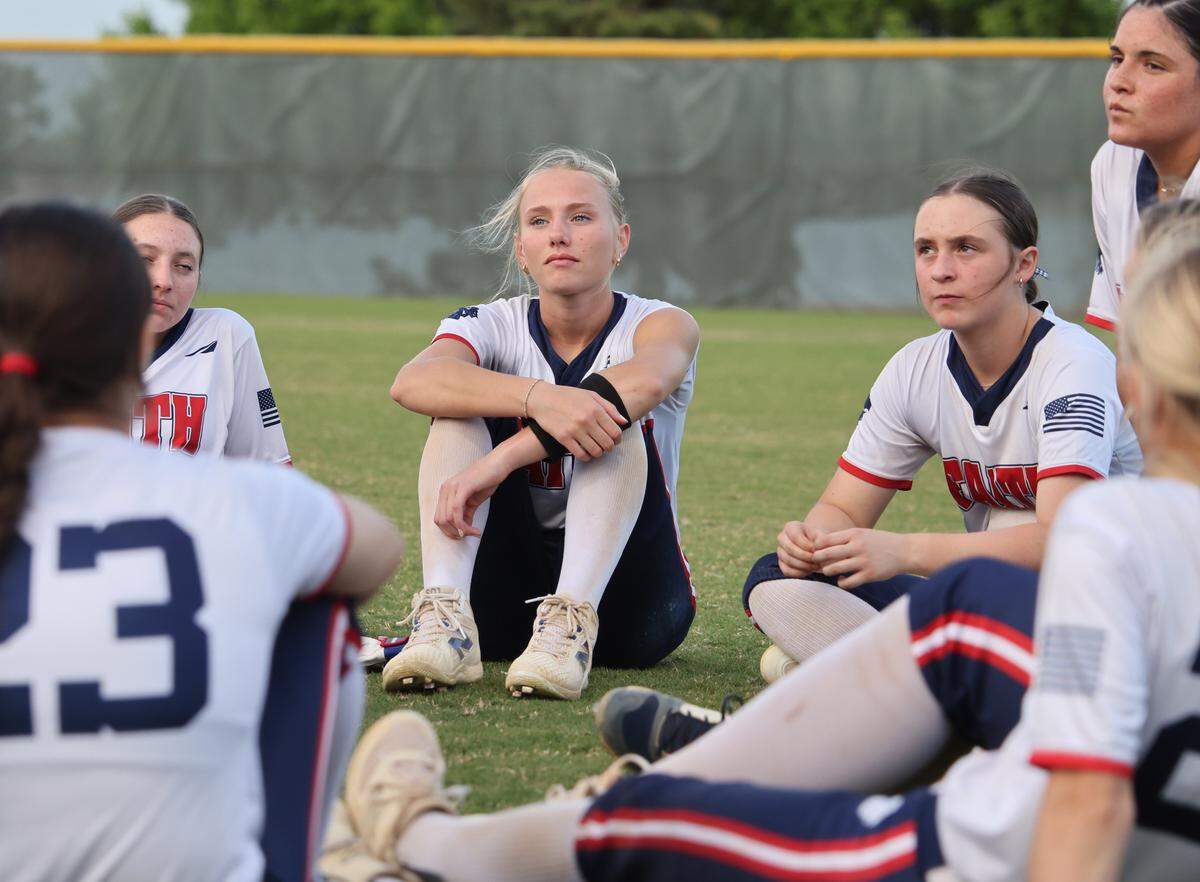 Grapevine Faith center fielder Michaela Hamilton sits and listens to head coach Kenny Bruce with team mates after winning a softball game at Oak Grove Park in Grapevine, Tx. Tuesday, March 31, 2026