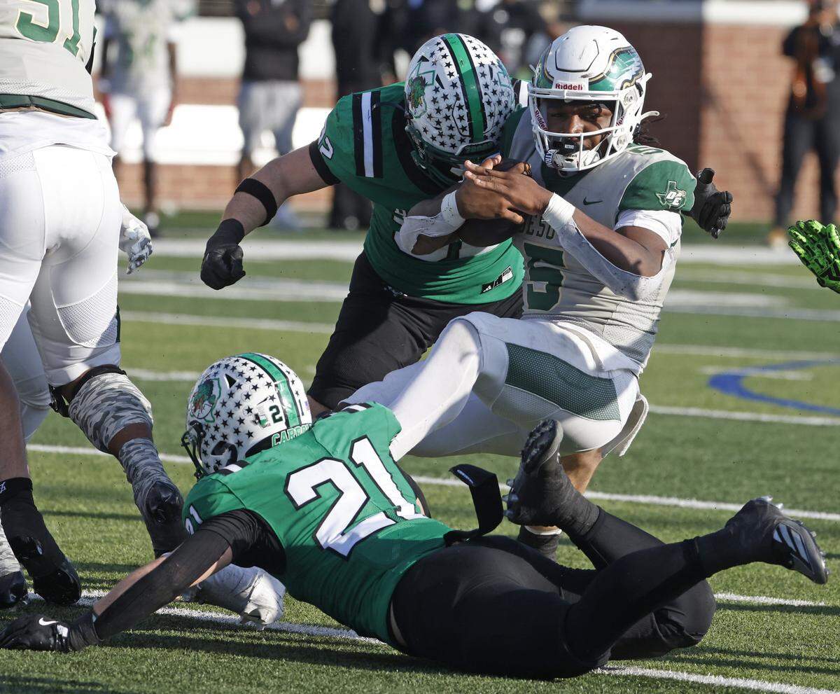 DeSoto running back SaRod Baker is brought down by Southlake Carroll linebackers William Leins (32) and Robbie Ladd (21) during the first half of a Class 6A Division II state semifinal Saturday at Newsom Stadium in Mansfield.