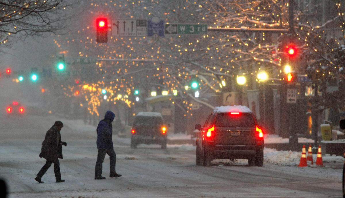 Pedestrians cross Houston Street downtown as snow continues to fall, Thursday evening February 11, 2010.