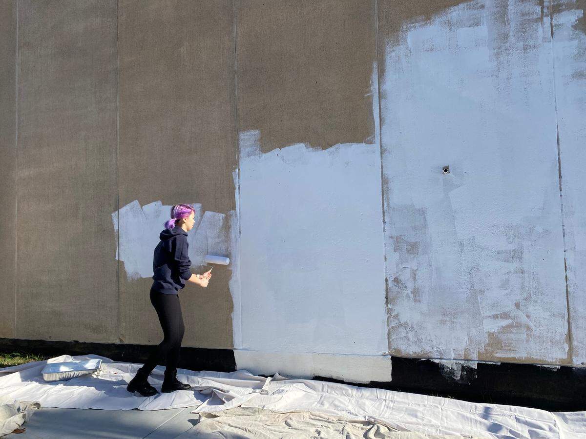 Anne Allen’s daughter helping prime a downtown wall for a mural.