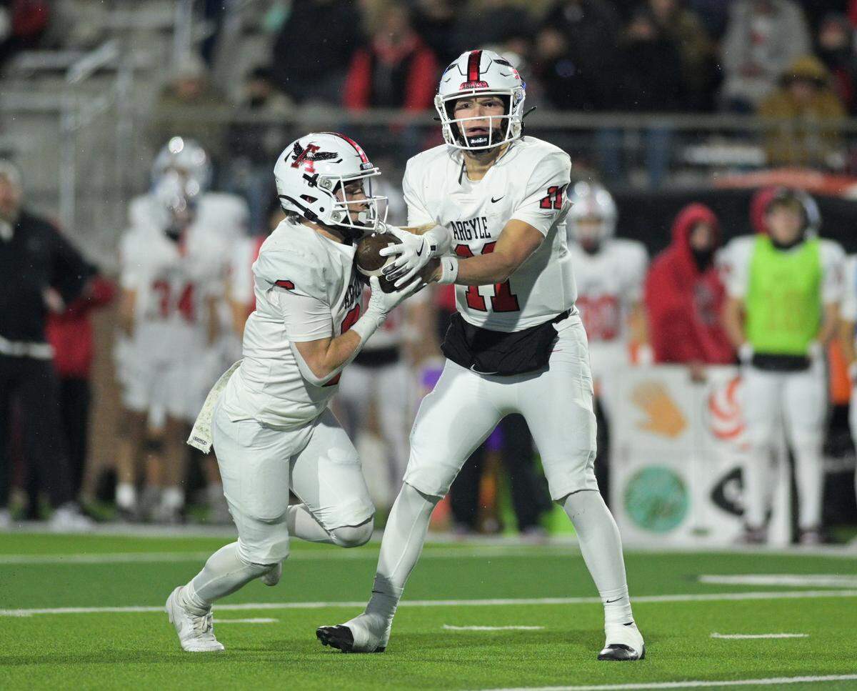 Argyle quarterback Maguire Gasperson (11) hands off the ball to running back Watson Bell (6) during the Class 5A Division II Region I playoff game against Lovejoy High School at Prosper ISD Children’s Health Stadium in Prosper, Texas on Friday, Dec. 6, 2024.