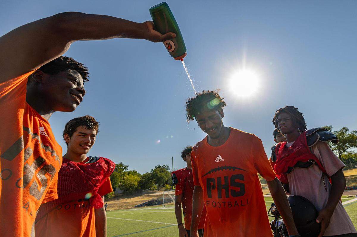 Abdel Mansour, 16, gets water poured on his head from his football teammates after practice at Fort Worth Polytechnic High School in Fort Worth on Thursday, Aug. 10, 2023.